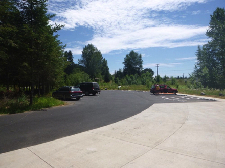 Main parking lot – two accessible parking spaces – sidewalk – hard surface walkway to trail